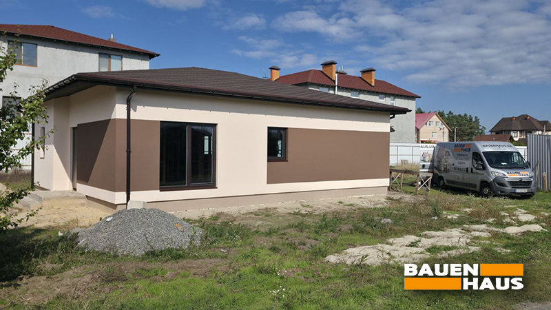 Завершений фасад одноповерхового SIP-будинку площею 89 м² із декоративними панелями коричневого кольору